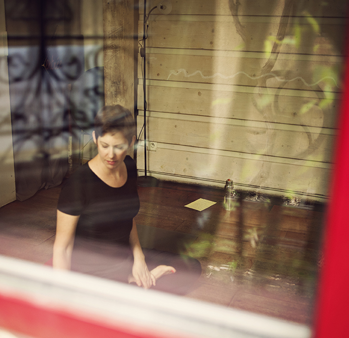 Julie, assise en lotus, vue au travers de la vitre du studio Redcygne