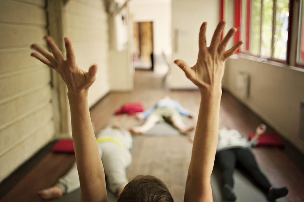 Cours de yoga, l'enseignante a les mains levées